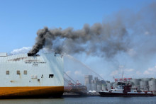 Hasičský čln rozprašuje vodu na nákladnú loď, kde dvaja hasiči z New Jersey zahynuli po tom, čo uviazli pri boji s požiarom v Port Newark, New Jersey. FOTO: Reuters