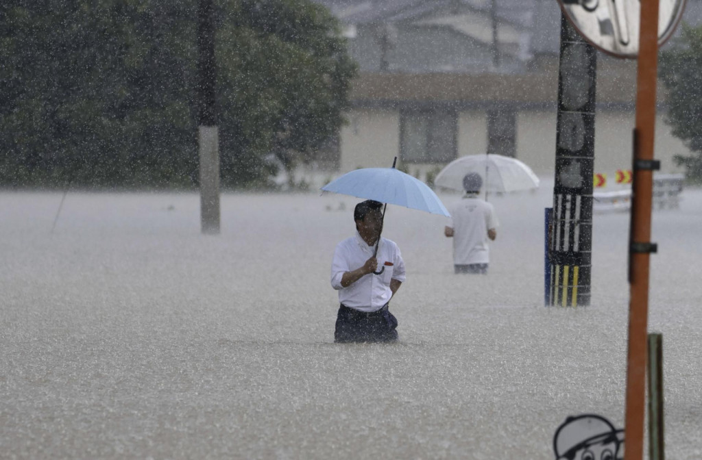 Ľudia sa brodia po zaplavenej ulici v Kumure, v prefekt&uacute;re Fukuoka na juhu Japonska. FOTO: TASR/AP