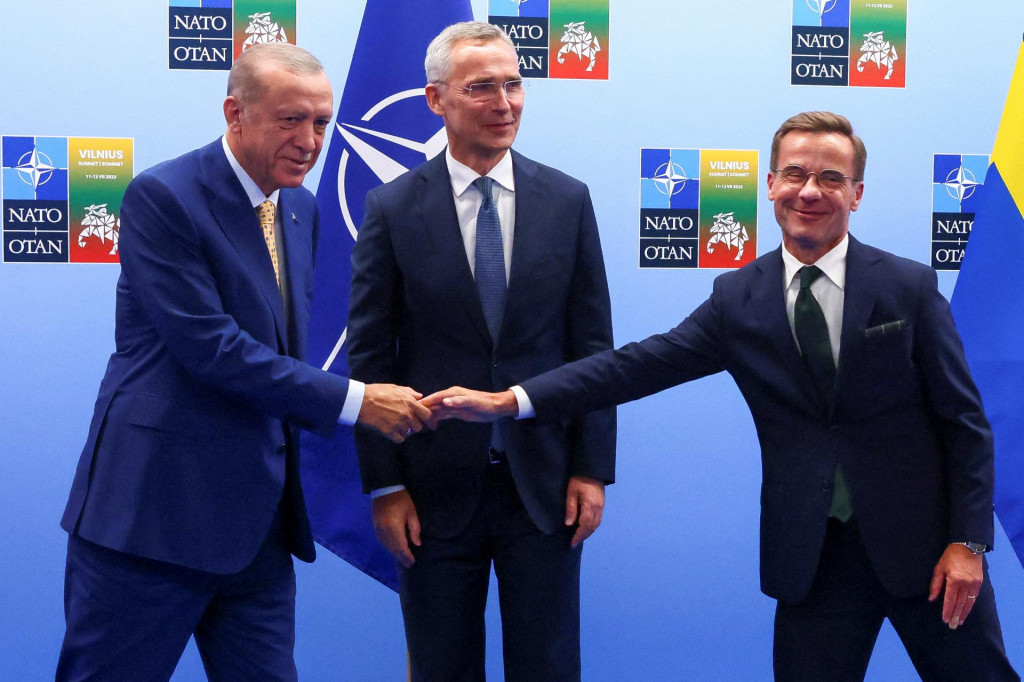 Turecký prezident Tayyip Erdogan a švédsky premiér Ulf Kristersson si podávajú ruky vedľa generálneho tajomníka NATO Jensa Stoltenberga. FOTO: Reuters