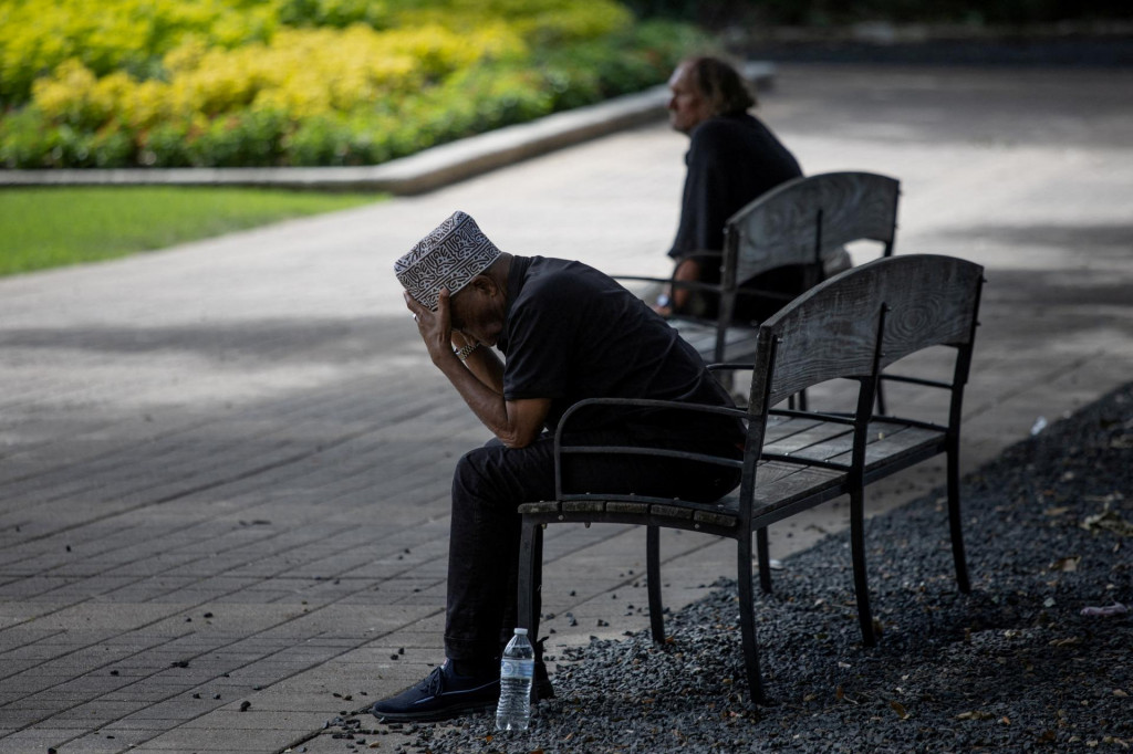 Muži sa počas horúceho počasia v centre Houstonu v Texase skrývajú na mestskej lavičke pod stromami. FOTO: Reuters