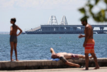 Ľudia sa opaľujú v blízkosti Krymského mosta, ktorého časť bola poškodená. FOTO: Reuters