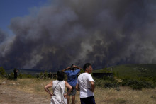 Miestni obyvatelia sledujú lesný požiar v obci Pournari pri gréckej metropole Atény v utorok 18. júla 2023. FOTO: TASR/AP