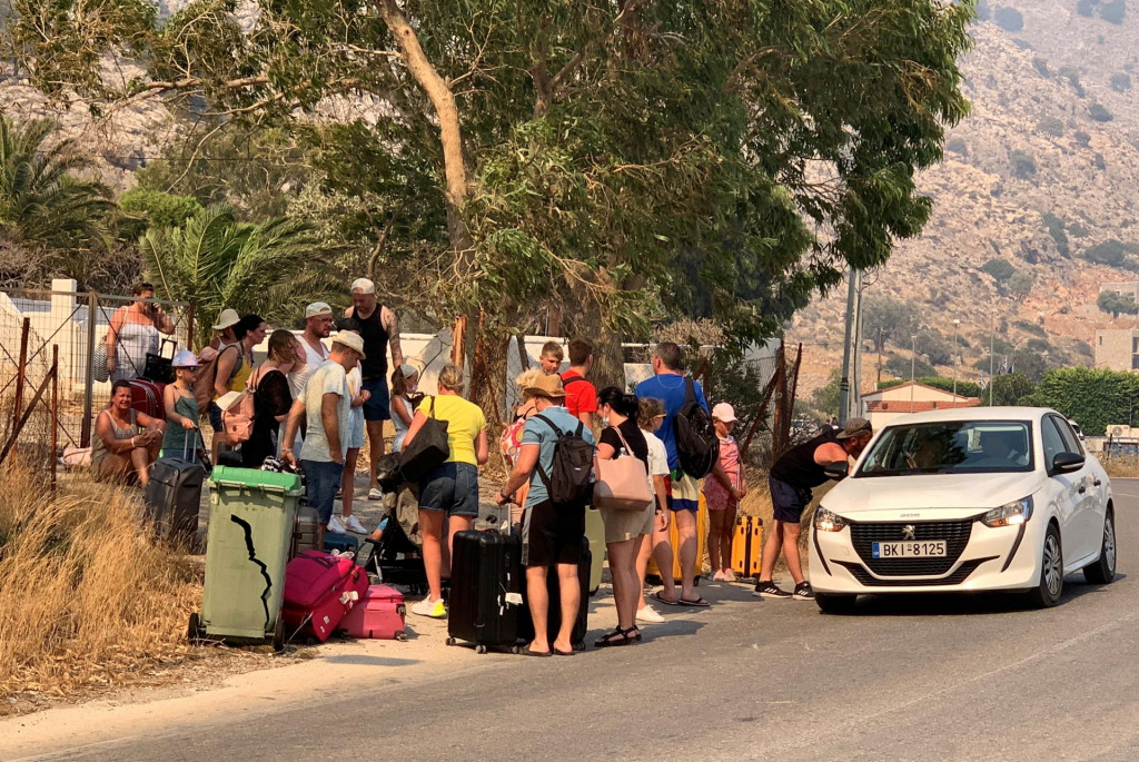 Evakuovaní turisti opúšťajú rezort blízko mesta Lindos. Podľa meteorológov majú extrémne horúčavy trvať ešte týždeň. FOTO: Reuters