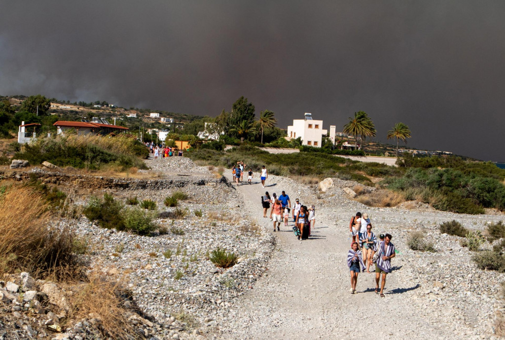 Turisti z dôvodu vypuknutia lesného požiaru opúštajú rezorty v meste Lindos. V pondelok podľa meteorológov nastane vo vlne horúčav v Grécku krátky oddych, v utorok sa však vysoké teploty vrátia a potrvajú minimálne do piatka. FOTO: Reuters