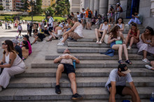 Ľudia oddychujú na schodoch budovy počas horúceho a slnečného dňa v Madride. FOTO: TASR/AP