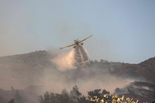 Hasičské lietadlo púšťa vodu na lesný požiar neďaleko dediny Vati na ostrove Rodos. FOTO: Reuters