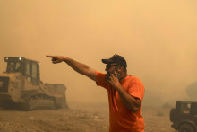 Dobrovoľník dáva pokyny počas hasenia lesného požiaru v obci Vati na ostrove Rodos na juhovýchode Grécka. FOTO: TASR/AP