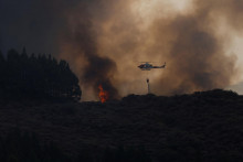 Pri hasení požiarov pomáhajú aj helikoptéry. FOTO: Reuters