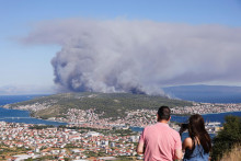 Ľudia sledujú požiar na ostrove Čiovo. FOTO: Reuters