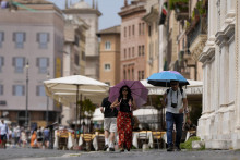 Turisti kráčajú s dáždnikmi počas horúceho dňa v Ríme. FOTO: TASR/AP
