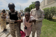 Policajti haitskej národnej polície pomáhajú žene zasiahnutej slzným plynom po tom, čo polícia pred americkým veľvyslanectvom v Port-au-Prince vyčistila tábor ľudí unikajúcich pred hrozbou ozbrojených gangov. FOTO: Reuters