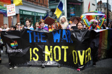 Ľudia kráčajú za protivojnovým transparentom počas Pride pochodu v Liverpoole. FOTO: Reuters