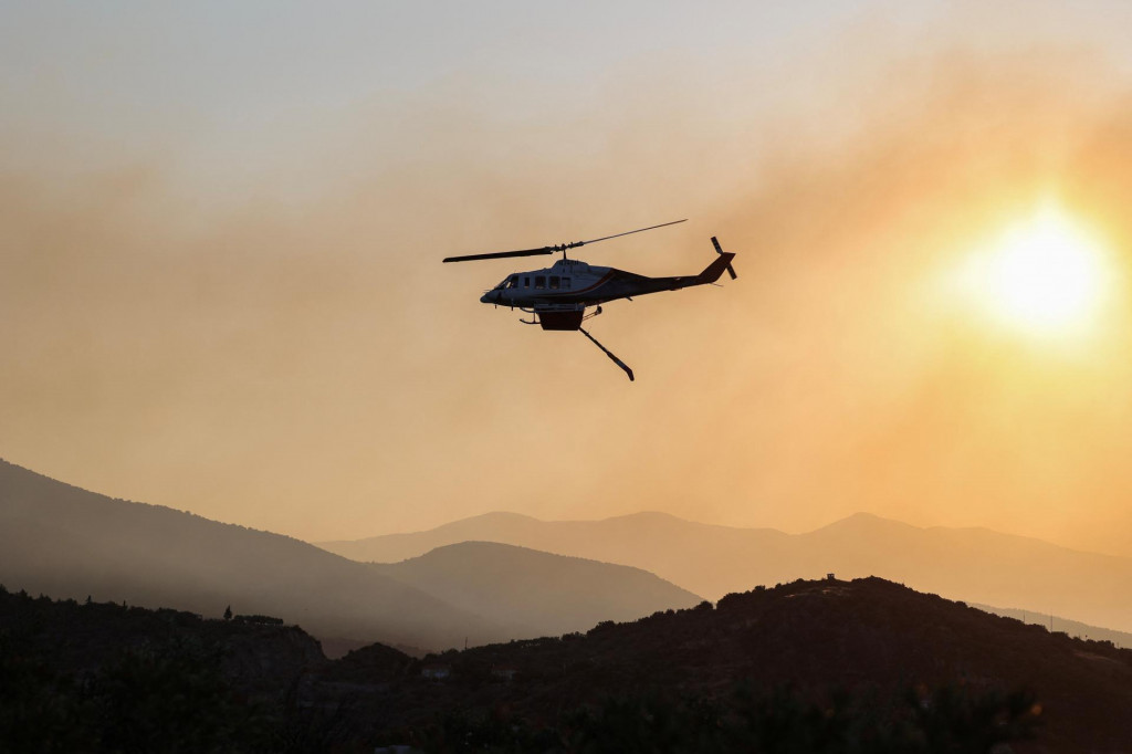 Hasičský vrtuľník letí, keď horí lesný požiar pri meste Volos, v strednom Grécku. FOTO: Reuters