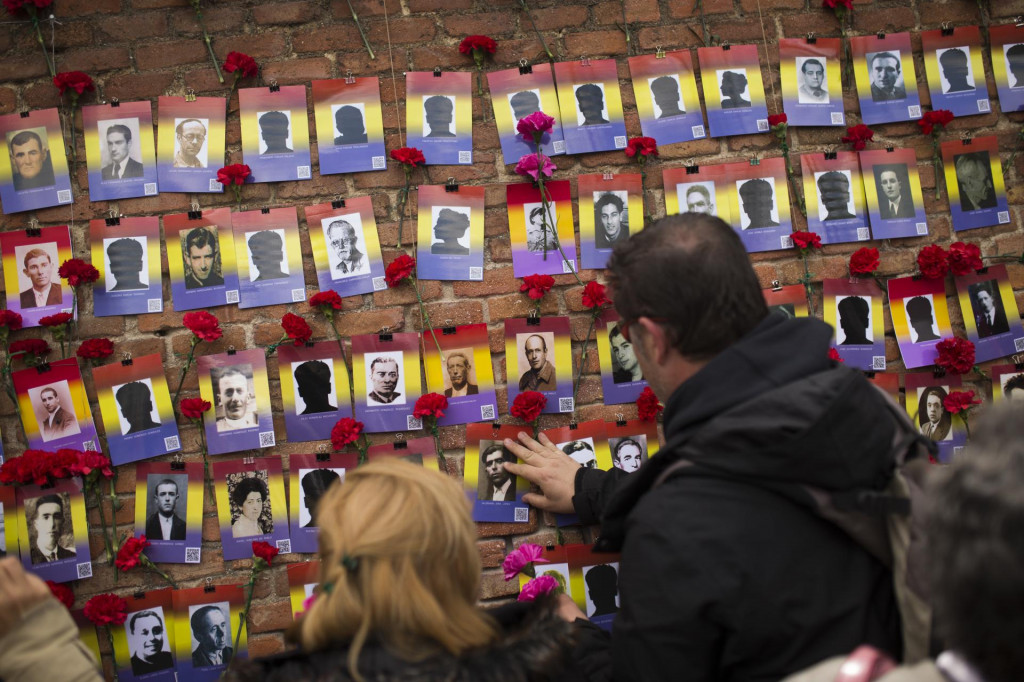 Ľudia kladú červené karafiáty vedľa fotografií obetí španielskej občianskej vojny na cintoríne v Madride. FOTO: TASR/AP