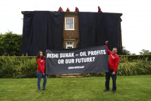 Aktivisti z organizácie Greenpeace, ktorí zakryli dom britského premiéra Rishiho Sunaka čiernou látkou v grófstve Severný Yorkshire. FOTO: TASR/AP