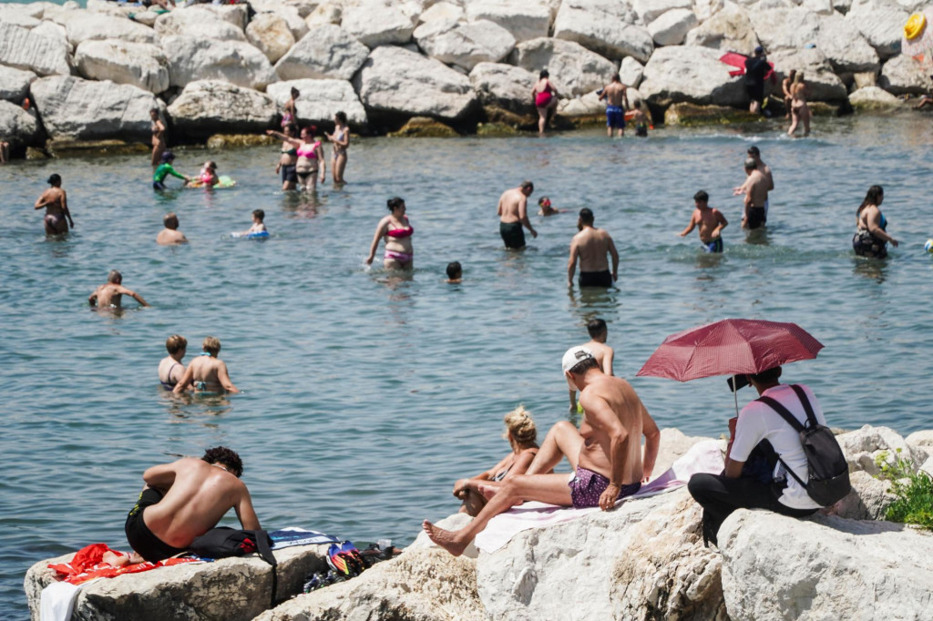 Ľudia trávia čas na pláži počas horúčav v Neapole na juhu Talianska. FOTO: TASR/AP