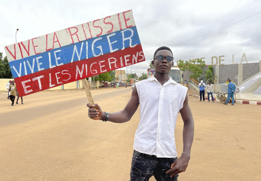 Stúpenec nigerskej vládnucej junty drží transparent vo farbách ruskej vlajky s nápisom ”Nech žije Rusko, nech žije Niger a Nigerčania” počas protestu v nigerskej metropole Niamey. FOTO TASR/AP