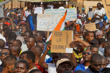Demonštranti držia ruskú vlajku a transparenty počas zhromaždenia na podporu pučistov v hlavnom meste Niamey v Nigeri. FOTO: Reuters