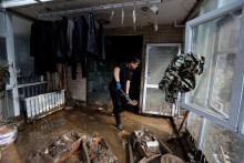 Priateľ miestneho obyvateľa menom Gao pomáha upratať jeho poškodený dom. FOTO: Reuters