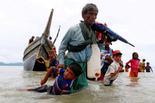 FILE PHOTO: A Rohingya refugee man pulls a child as they walk to the shore after crossing the Bangladesh-Myanmar border by boat through the Bay of Bengal in Shah Porir Dwip, Bangladesh, September 10, 2017. REUTERS/Danish Siddiqui/File Photo SNÍMKA: Danish Siddiqui