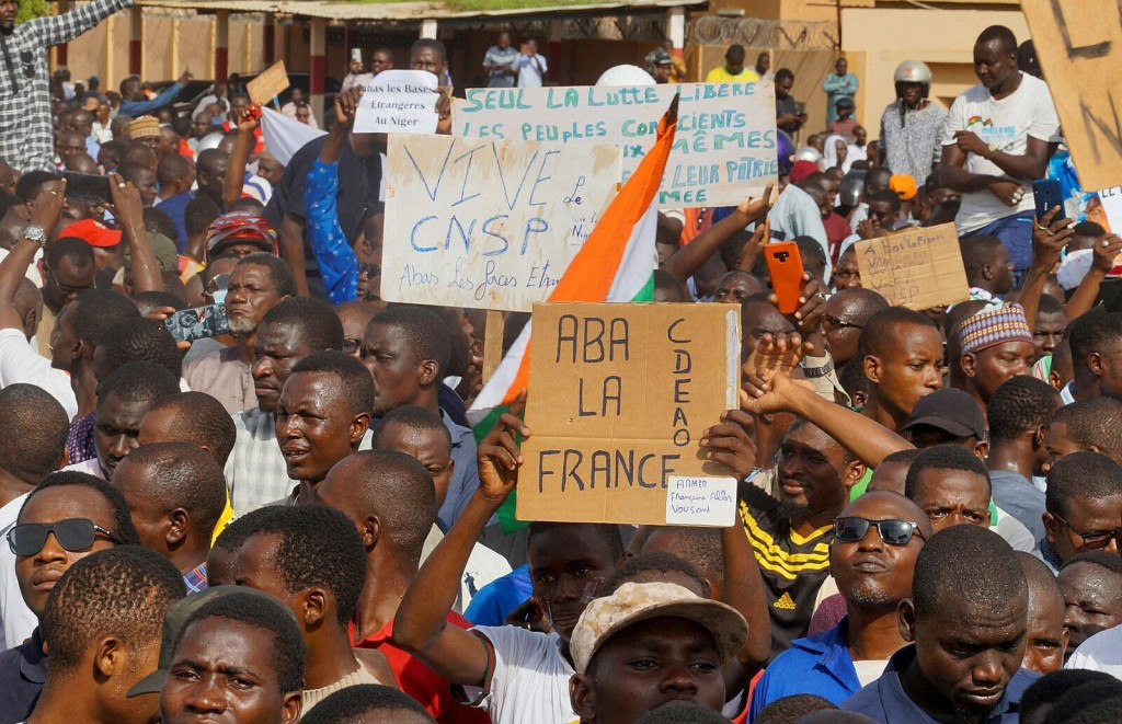 Demonštranti držia ruskú vlajku a transparenty počas zhromaždenia na podporu pučistov v hlavnom meste Niamey v Nigeri. FOTO: Reuters