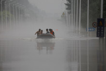 Ľudia jazdia loďou po zaplavenej ceste po dažďoch a záplavách, ktoré priniesli pozostatky tajfúnu Doksuri. FOTO: Reuters