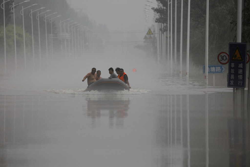 Ľudia jazdia loďou po zaplavenej ceste po dažďoch a záplavách, ktoré priniesli pozostatky tajfúnu Doksuri. FOTO: Reuters