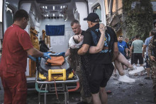 Muž odnáša do sanitky zranenú osobu. FOTO: TASR/AP