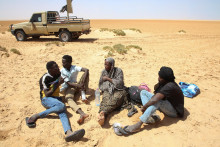 Tafaul Omar, tehotná 26-ročná zdravotná sestra zo Sudánu, sa rozpráva so skupinou mužov, keď uviazla v púšti na líbyjsko-tuniských hraniciach. FOTO: Reuters