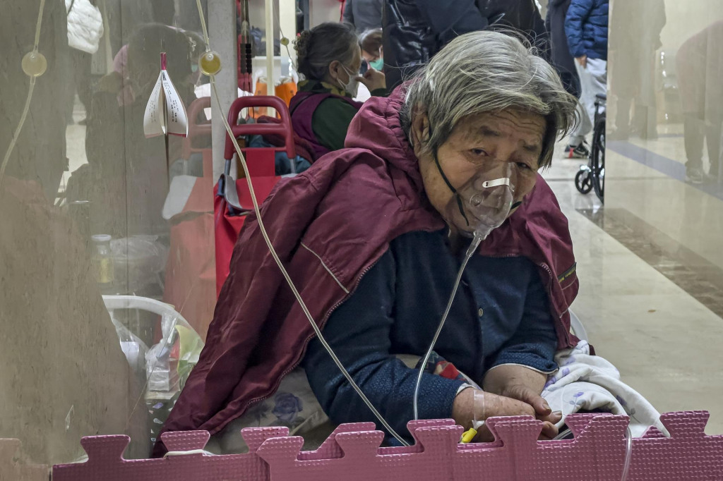 Staršia žena s kyslíkovou maskou na tvári dostáva infúziu na chodbe pohotovosti v Pekingu FOTO: TASR/AP