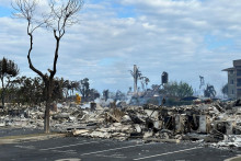 Hasič hasí horúce miesta v komplexe bytov Ho‘Onanea v dôsledku požiaru v Lahaine, Maui. FOTO: Reuters