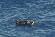 Štyria migranti mávajú o pomoc na Stredozemnom mori. FOTO: TASR/AP
