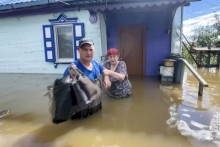 Záchranár pomáha obyvateľke zaplavenej dediny pri odchode z jej domu počas evakuácie v Prímorskom kraji na ruskom Ďalekom východe. FOTO: TASR/AP