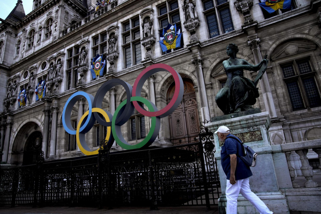 Muž kráča okolo olympijských kruhov pred radnicou jeden rok do slávnostného otvorenia olympijských hier 2024 v Paríži.