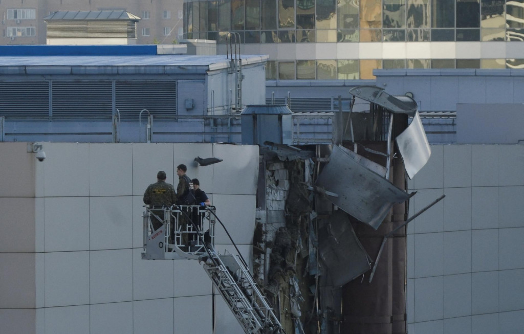 Vyšetrovatelia pri poškodenej streche po zostrelení ukrajinského bezpilotného lietadla v Moskve. FOTO: REUTERS
