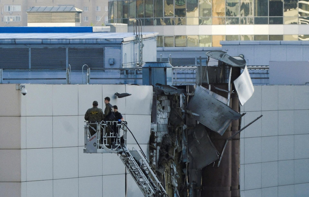 Vyšetrovatelia pracujú v blízkosti poškodenej strechy po ohlásenom zostrelení bezpilotného lietadla v Moskve. FOTO: Reuters
