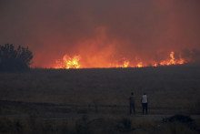 Ľudia sledujú plamene počas lesného požiaru neďaleko gréckeho mesta Alexandroupoli. FOTO: TASR/AP