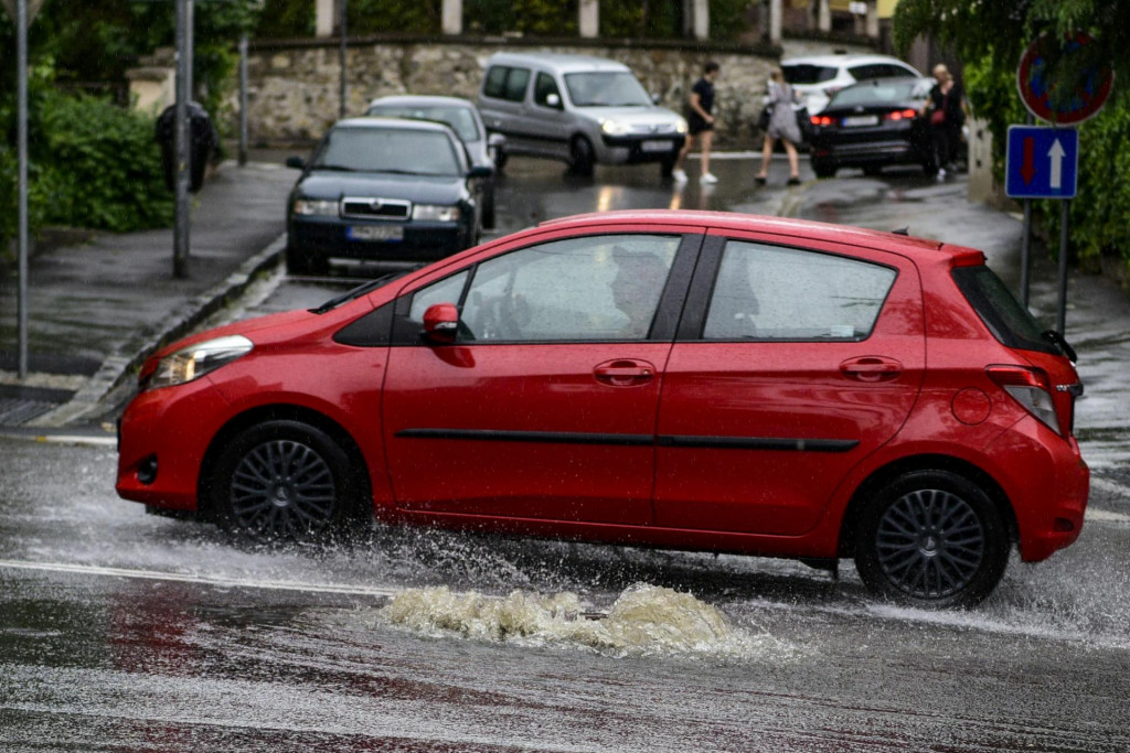 Na snímke auto prechádza po zaplavenej ceste počas silného dažďa v Bratislave.