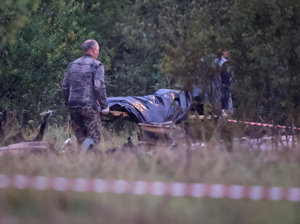 Pohotovostní špecialisti nesú tašku na telá blízko vrakov súkromného lietadla spojeného s veliteľom wagnerovcov Jevgenijom Prigožinom na mieste havárie Tverskej oblasti. FOTO: Reuters