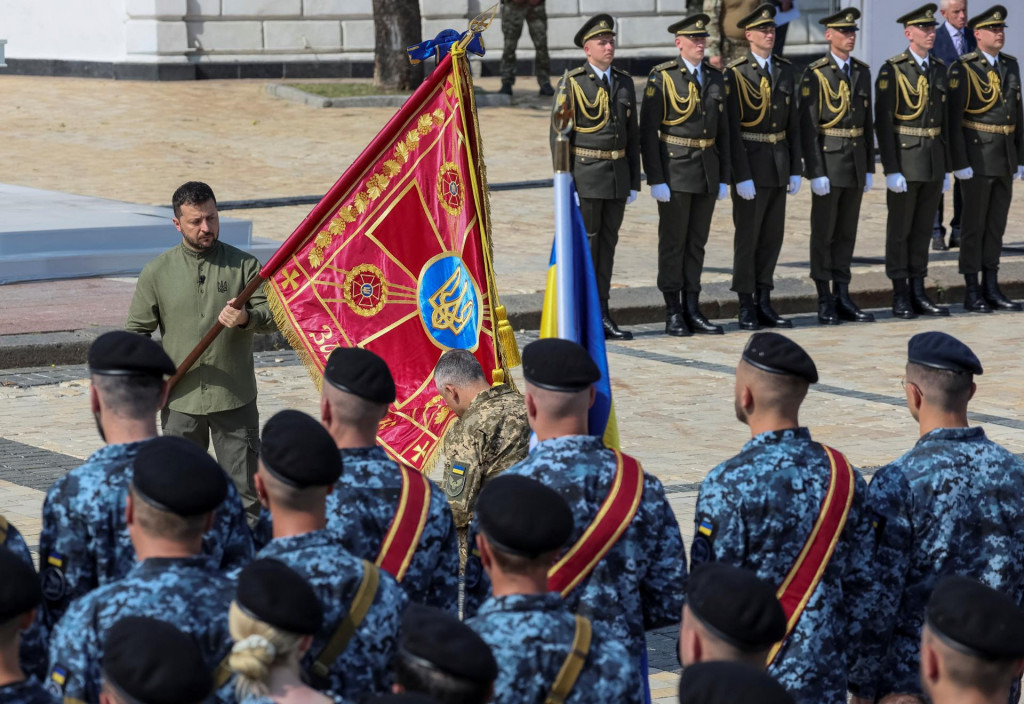 Ukrajinský prezident Volodymyr Zelenskyj odovzdáva vlajku vojakovi počas slávnostného ceremoniálu Dňa nezávislosti Ukrajiny. FOTO: Reuters