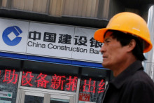 Pracovník prechádza okolo pobočky China Construction Bank v Pekingu. FOTO: REUTERS