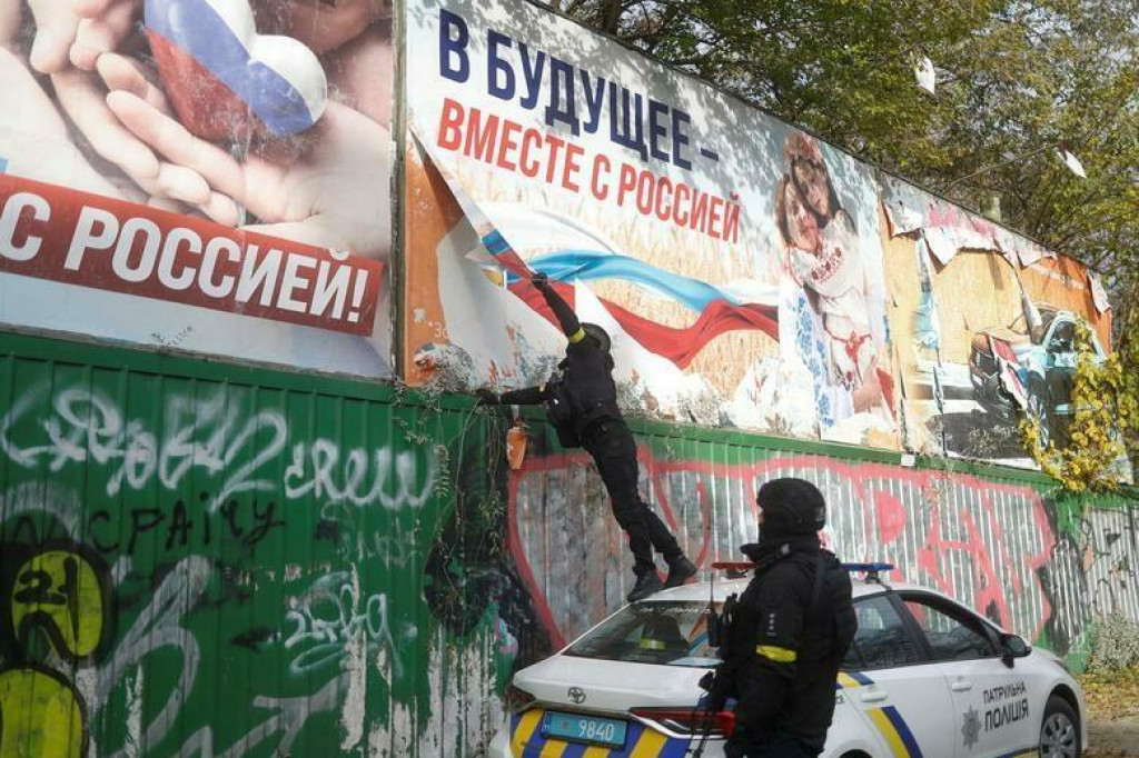 Ukrajinskí policajti po ústupe Ruska z ukrajinského Chersonu trhajú v meste bilbordy ruskej propagandy. FOTO: Reuters