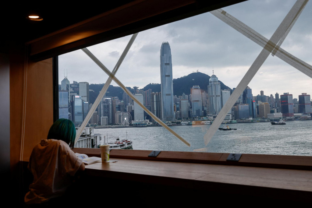 Dievča číta knihu v kníhkupectve, ktorého okná sú prelepené páskou v očakávaní tajfúnu Saola v Hong Kongu. FOTO: Reuters