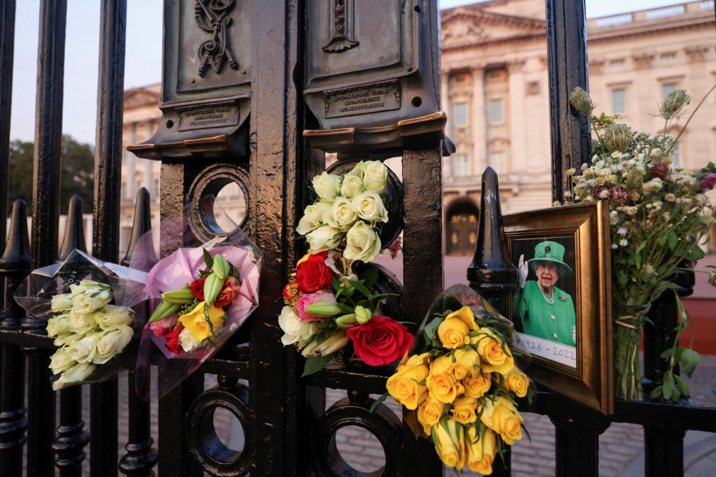 Obraz a kvetinové pocty položené pred Buckinghamským palácom na prvé výročie smrti kráľovnej Alžbety II. FOTO: Reuters
