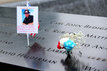 Fotografia hasiča Scotta A. Larsena a kvety ležia pri pamätníku obetí teroristických útokov Svetového obchodného centra. TASR/AP