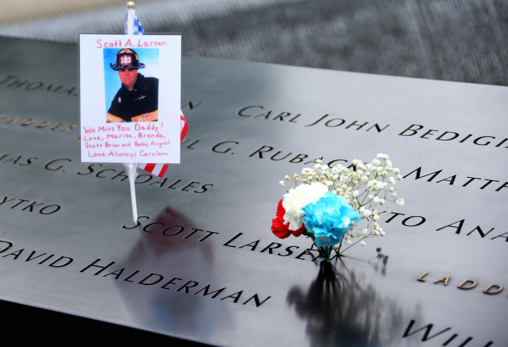 Fotografia hasiča Scotta A. Larsena a kvety ležia pri pamätníku obetí teroristických útokov Svetového obchodného centra. TASR/AP
