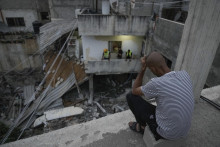 Palestínčania si prezerajú materiálne škody na budove po razii izraelskej armády v utečeneckom tábore Nur Šams. FOTO: TASR/AP