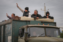 Utečenci z oblasti Náhorného Karabachu jazdia na korbe nákladného auta, keď prichádzajú do pohraničnej dediny Kornidzor v Arménsku. FOTO: Reuters