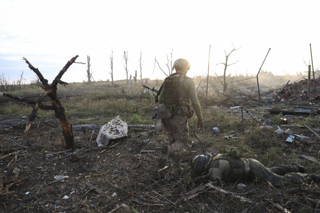 Veliteľ z 3. samostatnej ukrajinskej útočnej brigády kráča okolo mŕveho tela ruského vojaka na frontovej línii v dedine Andriivka pri meste Bachmut. FOTO: TASR/AP