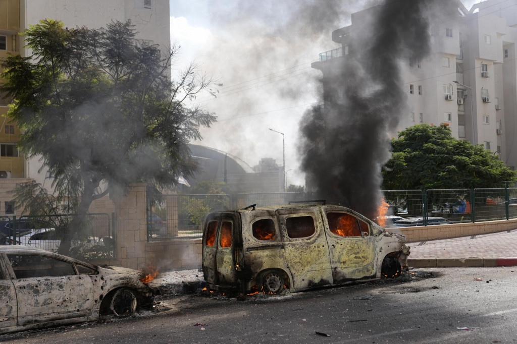 Horiace autá na ulici po tom, ako ich zasiahli rakety vystrelené z pásma Gazy v izraelskom meste Aškelon. FOTO: TASR/AP